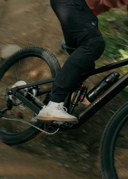 Mountainbiker fährt auf einem Raymon Rokua über einen Waldweg in die Kurve, Fokus auf die Wasserflasche am Rahmen
