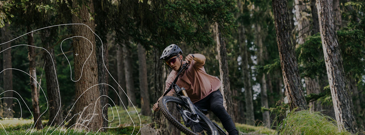 Mountainbiker fährt mit dem RAYMON ROKUA eine enge Kurve auf einem Waldtrail, links überlagert von weißen Höhenlinien im Stil einer topografischen Karte.