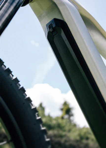 Detailaufnahme von der Unterseite des Rahmens eines silbernen Raymon Durok E-Mountainbikes, in den die schwarze Batterie integriert ist.