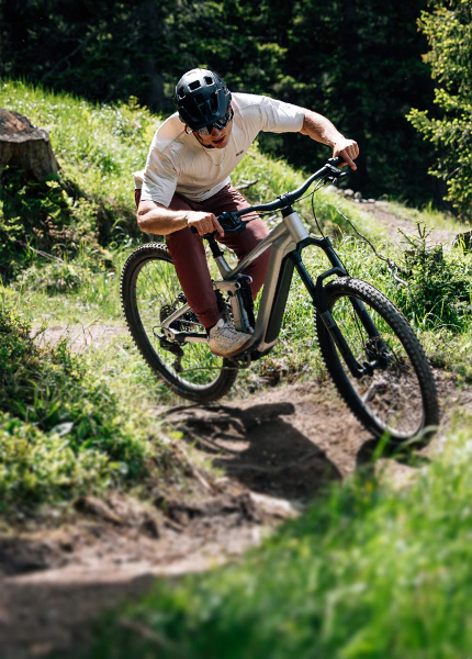 Ein Mountainbiker fährt mit einem Raymon Durok E-Bike einen steilen Waldweg hinunter.