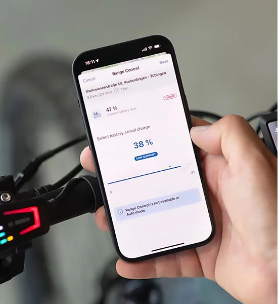 Smartphone zeigt die Bosch eBike Flow App mit Reichweiten-Management am Fahrradlenker.