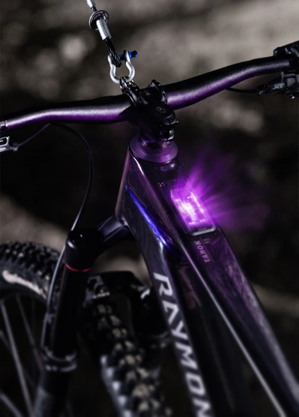 Raymon Tarok E-Mountainbike mit im Oberrohr integriertem, violett leuchtendem Display.