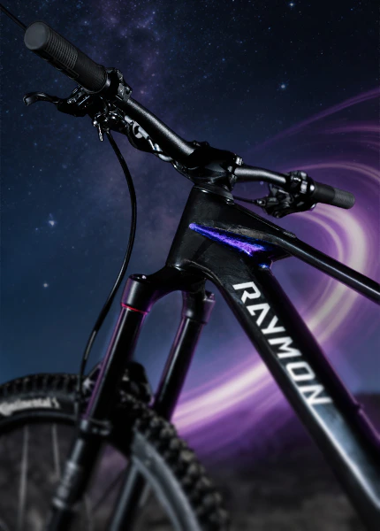 Raymon Tarok E-MTB mit schwarzem Carbonrahmen und galaktischen Akzenten vor einem Sternenhimmel.
