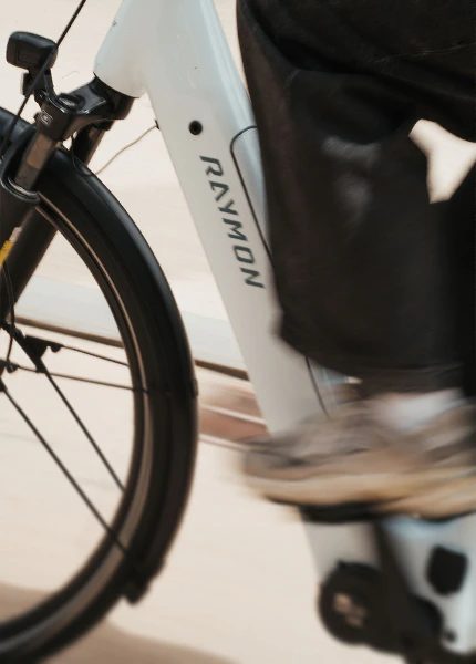 Nahaufnahme eines weißen Raymon Numa E-Bikes mit integriertem Rahmenmotor während der Fahrt.