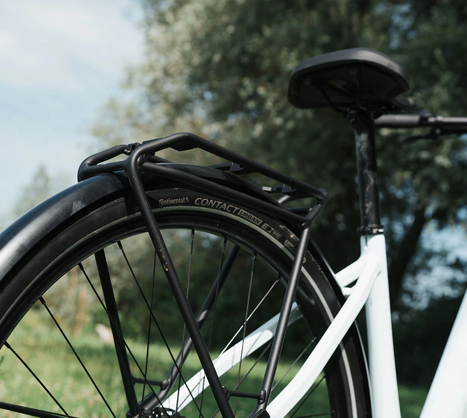Schwarzer Gepäckträger montiert über dem Hinterrad eines weißen Numa E-Bikes.