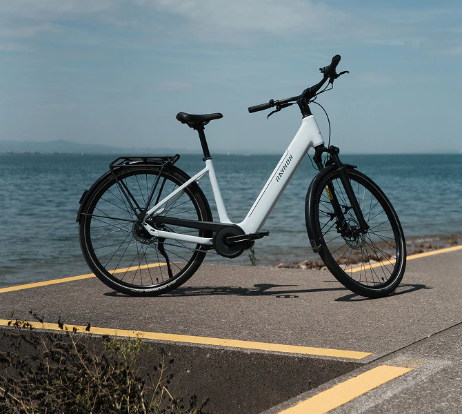 RAYMON NUMA Urban E-Bike in Weiß mit tiefem Einstieg auf einem Radweg am See