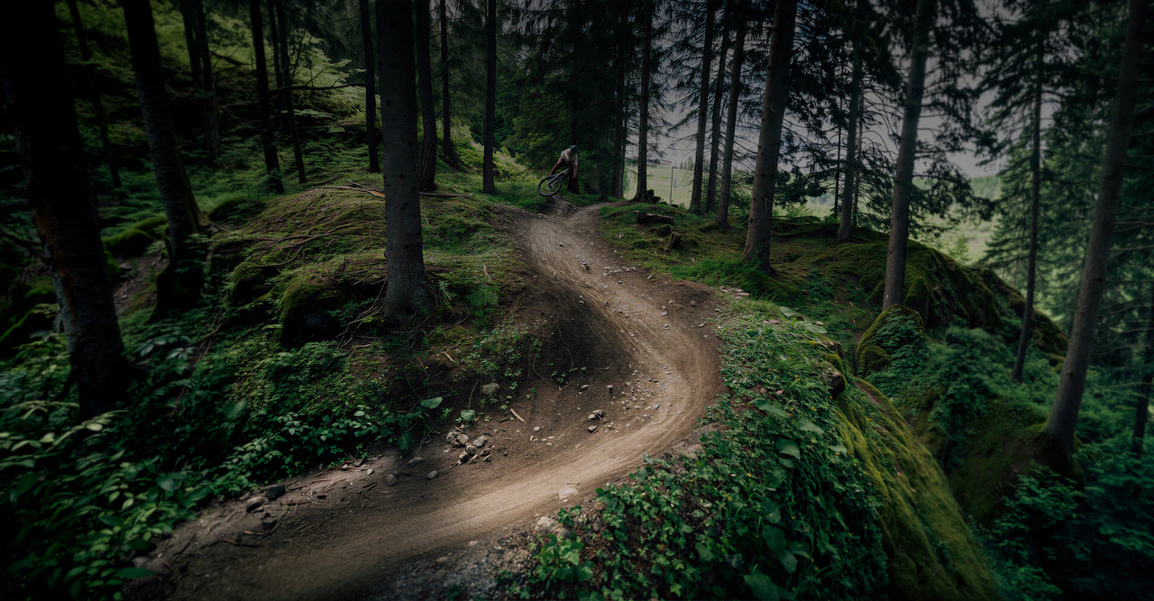 Zwei Personen fahren mit Raymon Durok E-Mountainbikes über eine Bergwiese vor einem Alpenpanorama.