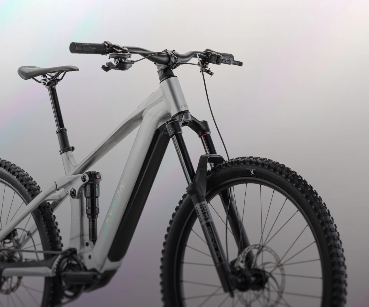 Silbernes Raymon Durok E-Mountainbike mit RockShox Federgabel vor Perlmutt-Hintergrund.