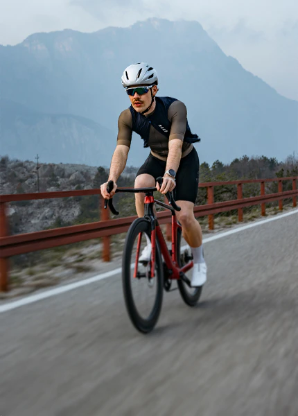 Rennradfahrer fährt auf einem roten Raymon Arva Ultra Highlight-Rahmen eine Bergstraße entlang.