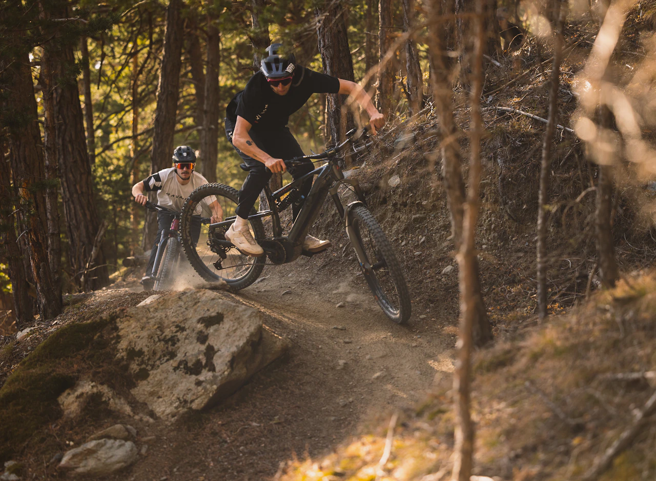 Zwei Mountainbiker fahren mit ihren Raymon Bicycles über einen staubigen Waldtrail.