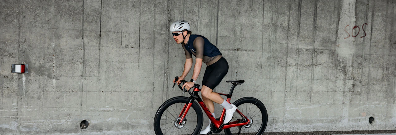 Mountainbiker mit Helm fährt rasant auf einem Raymon E-MTB durch einen Nadelwald.