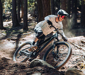 Mountainbiker fährt mit einem Raymon Tarok E-Bike rasant durch einen Wald.