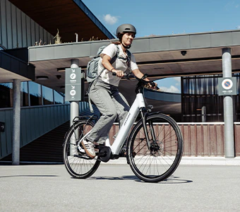 Junge Frau mit sportlichen Schuhen und schwarzer Hose fährt auf einem weißen Numa E-Bike durch die Stadt.